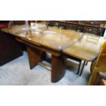 An Art Deco style walnut veneered draw-leaf dining table, set on curved standard ends with uniting