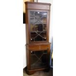 An Edwardian inlaid mahogany corner cabinet with canted sides and shelves enclosed by two astragal