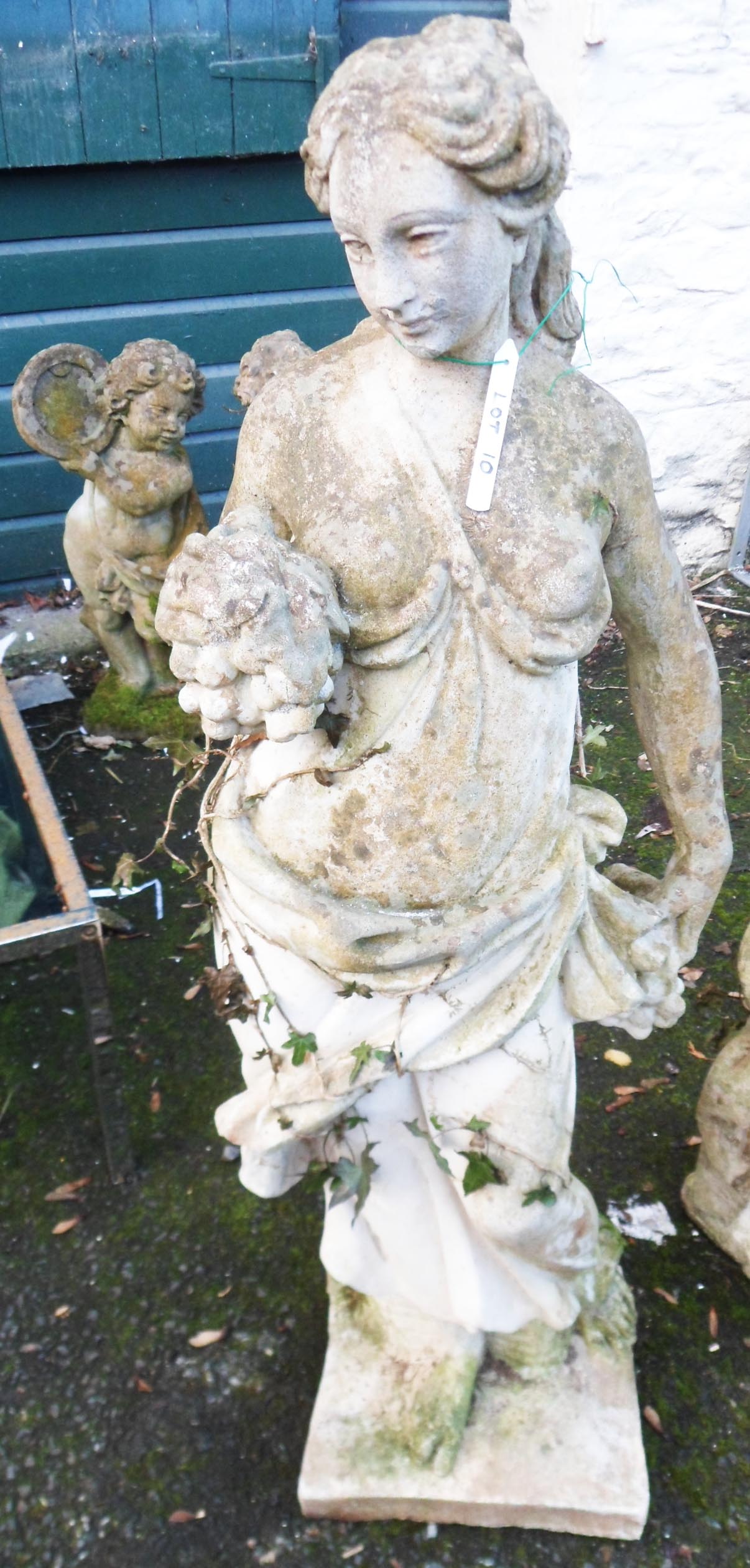 A 4' concrete garden statue of a classical maiden holding bunches of grapes