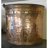 An antique copper bucket with riveted seamed body and brass swing handle