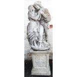 A cast concrete garden statue in the form of a courting couple, set on a decorative pedestal