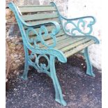 A modern painted cast iron framed garden elbow chair with wooden slats and pierced sides