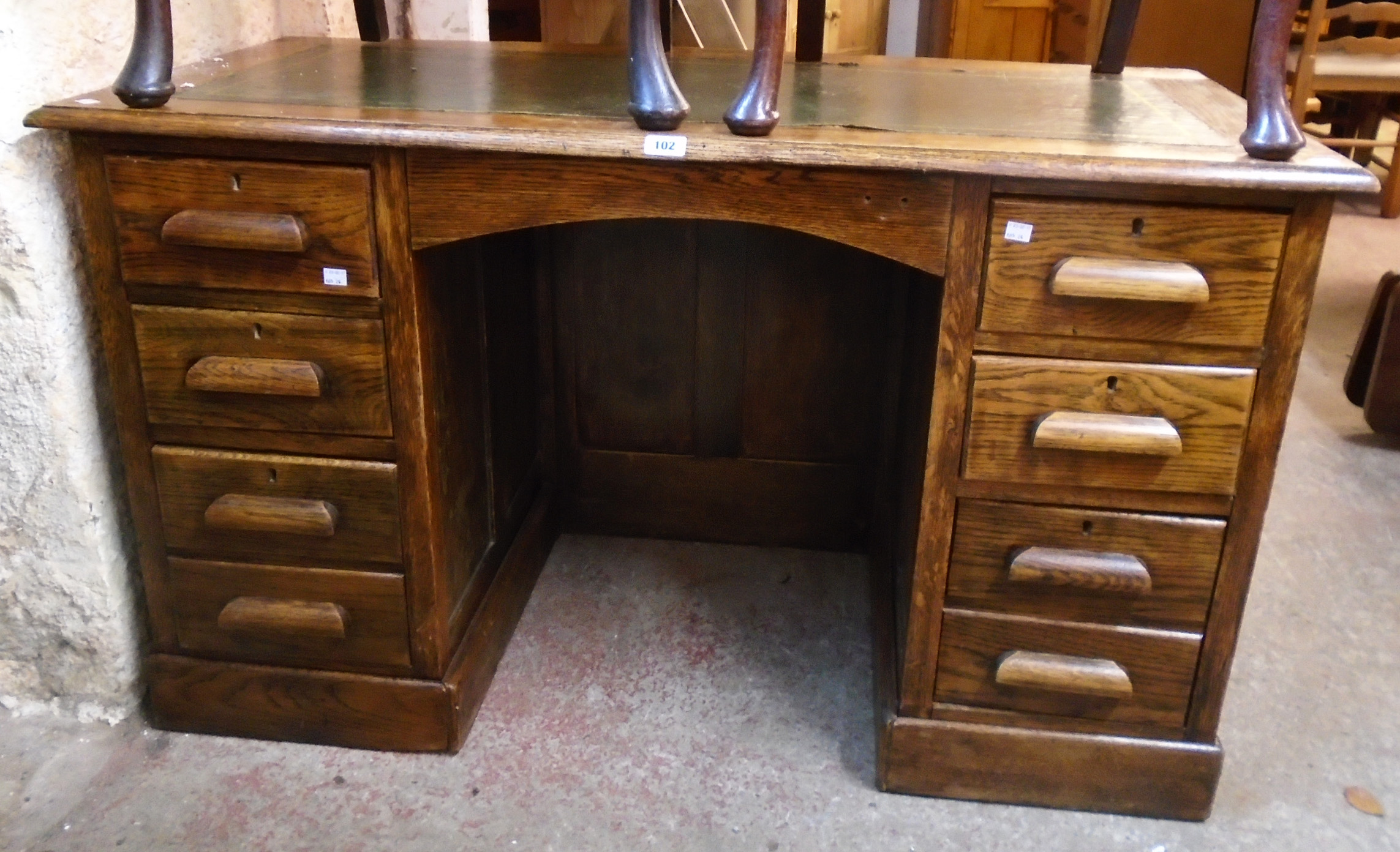 A 4' 3" 20th Century polished oak kneehole desk with remains of green leather inset top, panelled