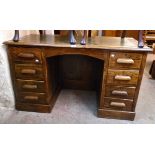 A 4' 3" 20th Century polished oak kneehole desk with remains of green leather inset top, panelled