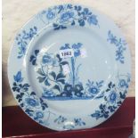 A 13" diameter antique English Delftware charger with central peony panel and border - minor chips