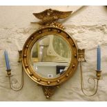 A reproduction Regency style gilt framed bevelled circular wall mirror with eagle shaped pediment,