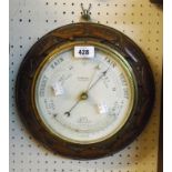 A 12" diameter late Victorian carved oak framed aneroid wall barometer/thermometer marked for A.