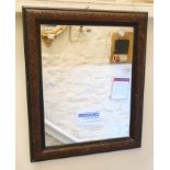 A stained wood framed wall mirror with pressed floral decoration