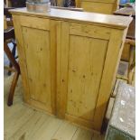 A 30 1/2" waxed pine wall cabinet with shelves enclosed by a pair of panelled cupboard doors