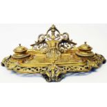A Victorian brass desk stand with central Green Man mask to back, profuse pierced scroll decoration,