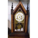 An American mixed stained wood cased shelf clock with gilt decorated glass door panel, visible