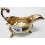 A Georgian silver sauce boat with shaped rim and cast scroll handle, set on acanthus topped legs