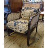 An early 20th Century mahogany framed bergere armchair with double skin sides, moulded harebell