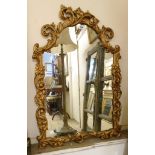 An ornate gilt resin framed wall mirror with shaped plate with acanthus scroll and floral