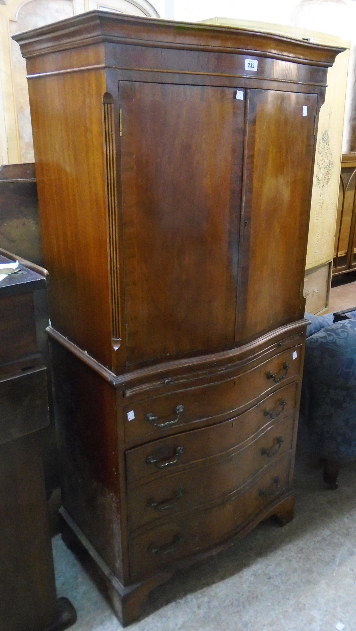 A 28 1/4" reproduction mahogany two part serpentine front drinks cabinet in the style of a