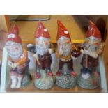 A set of four 18" painted and glazed ceramic gnomes in various poses