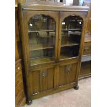 A 36" 1930's polished oak display cabinet with three shelves enclosed by a pair of glazed panel