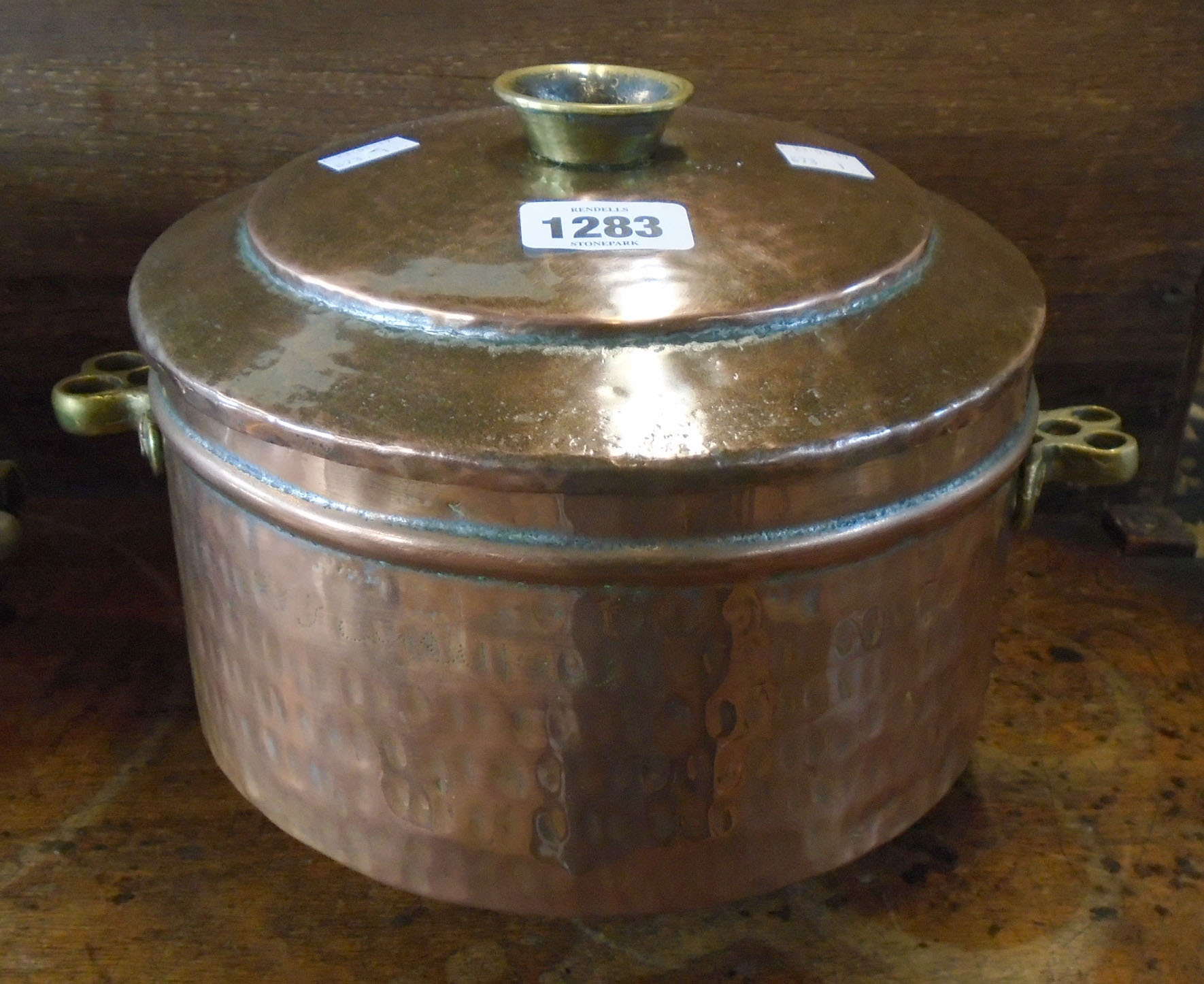A hammered copper lidded cooking pot with brass handles