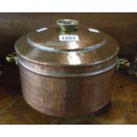 A hammered copper lidded cooking pot with brass handles