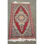 A Belgian machine made Rajah mat of typical design, white, cream, blue and green on red ground -