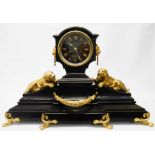 A 21" late Victorian ornate black slate cased mantel clock with gilt mask handles, flanking models