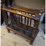 A 20 1/2" antique stained wood Canterbury with turned finials, spindle dividers and moulded base,