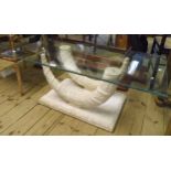 A 3' 8" glass top coffee table, set on a cast twin elephant tusk pattern base