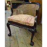 A 1920's carved stained beech framed tub chair with rattan back and seat panels, upholstered cushion