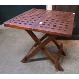 A stained hardwood folding table with pierced top and X-frame base