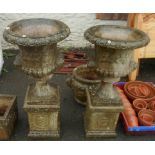 A pair of Sandford garden Classical style urns with mask decoration, set on square pedestals - 3' 6"
