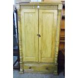 A 3' 7" 19th Century wood grained pine wardrobe with hanging space enclosed by a pair of fielded