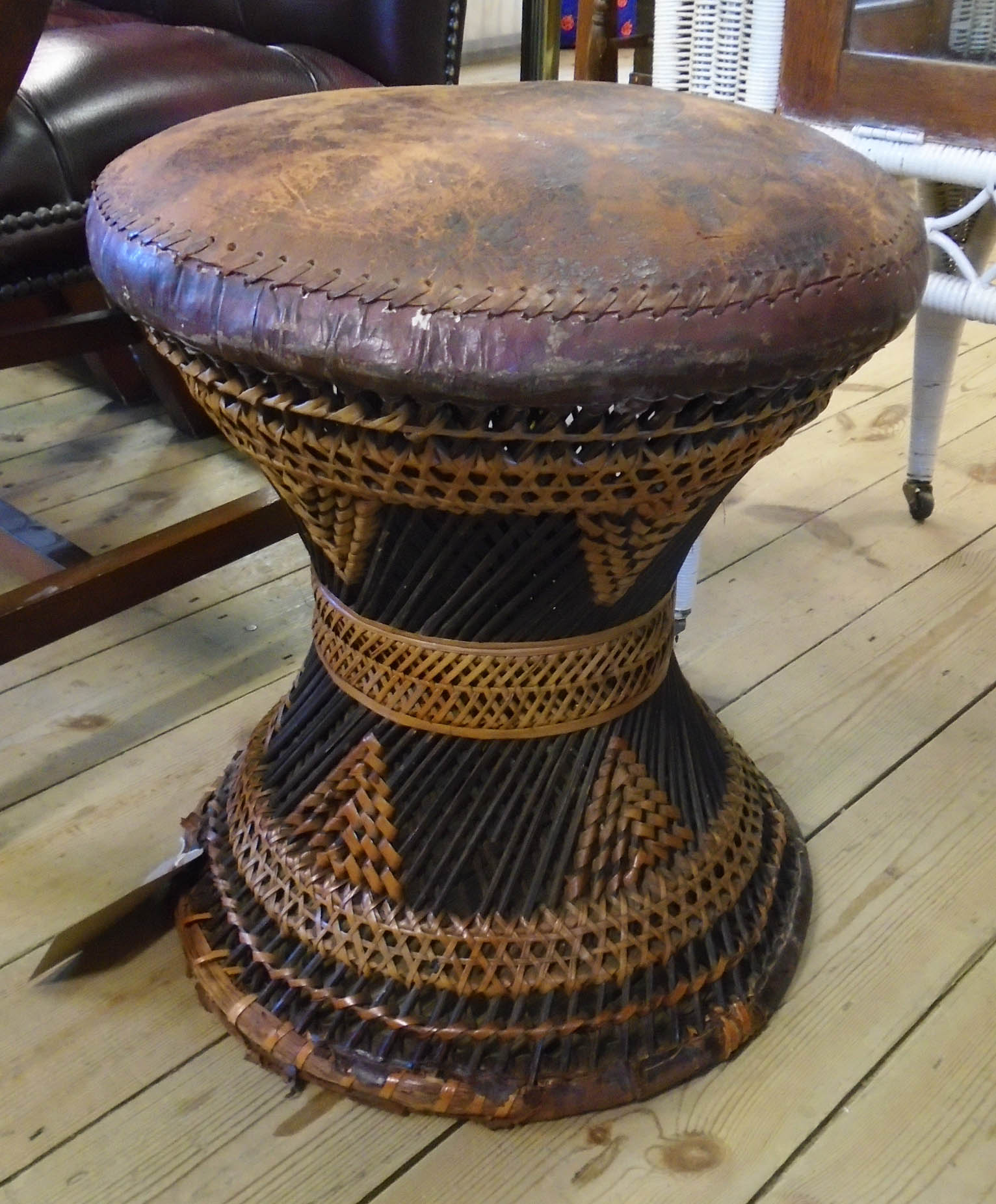 A North African decorative canework framed drum stool with stitched leather seat panel and repeat