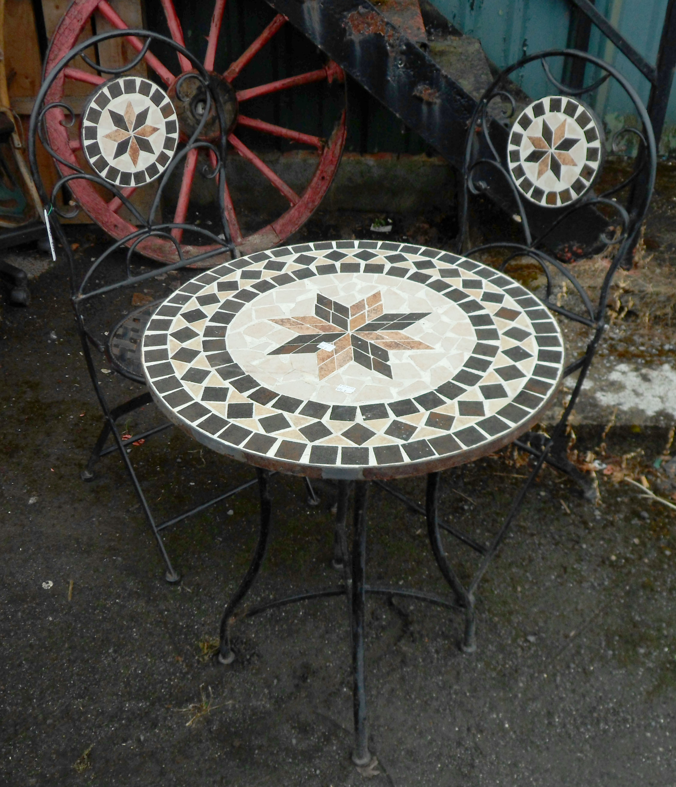 A wrought iron patio table and pair of chairs with mosaic decoration