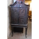 A 3' 3" antique Flemish style carved and stained wood cabinet on stand with broken pediment and