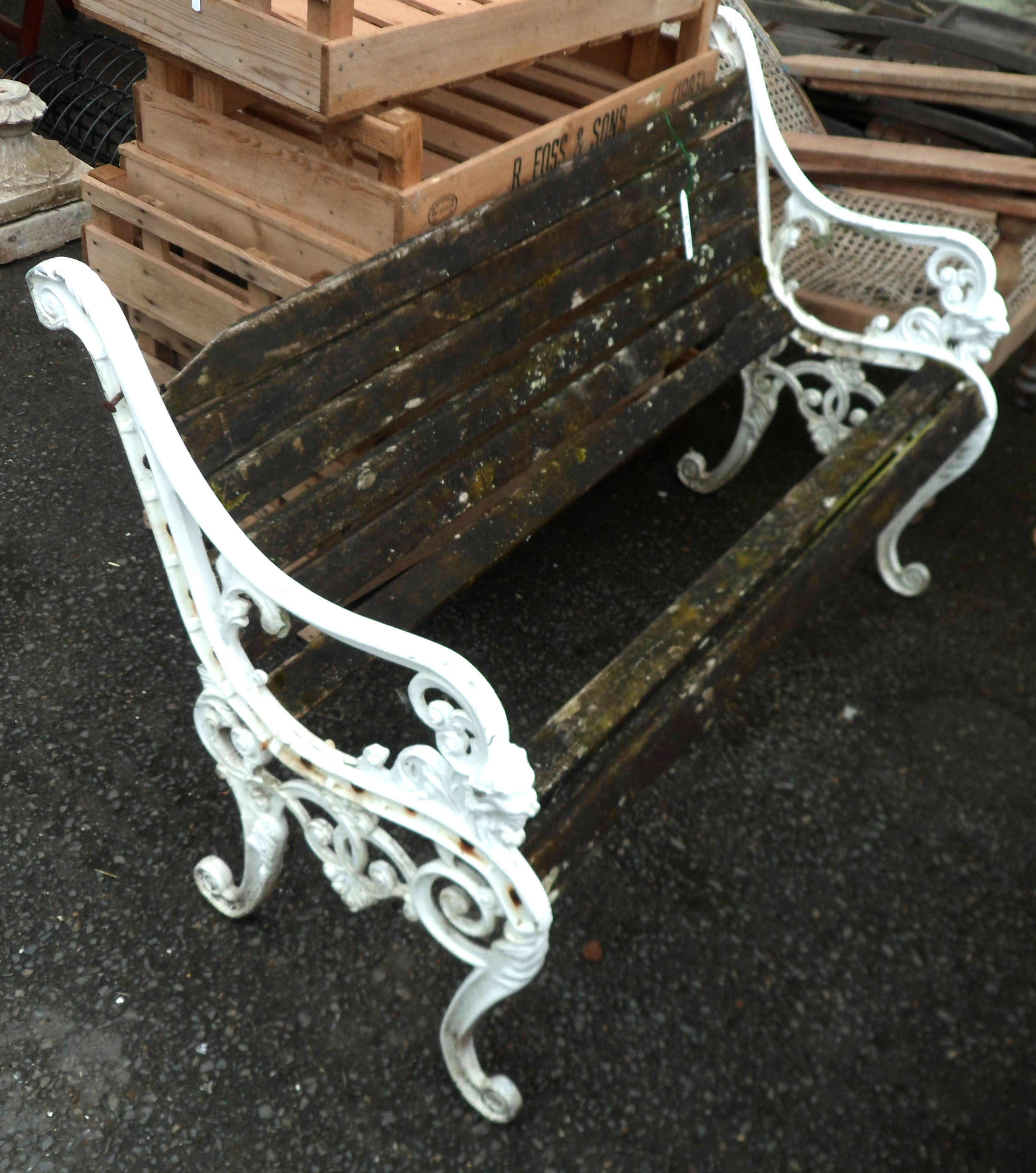A reproduction cast metal garden bench with remains of wooden slats