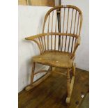 An old stripped wood comb back rocking chair with solid elm seat and crinoline stretcher