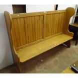 A 6' polished golden oak settle with panelled back, solid seat and shaped sides