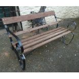 A garden bench with wrought iron scroll ends and wooden slats