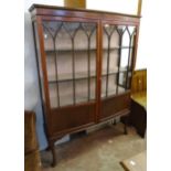 A 4' early 20th Century mahogany bow front display cabinet with material lined shelves enclosed by a