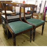 A pair of late Regency mahogany framed dining chairs with upholstered drop-in seats, set on turned