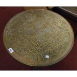 A 24" diameter Islamic brass topped occasional table, set on a stained wood folding base