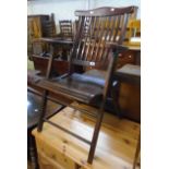 An early 20th Century stained wood folding framed stick back elbow chair, with slatted seat