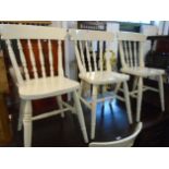 A set of four Windsor style kitchen chairs with spindle backs, solid seats and later painted finish,