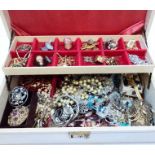 A white concertina jewellery box containing a quantity of good quality costume jewellery, badges and