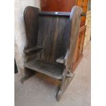 A 28½" elm pegged framed single seat wing back settle with curved panelled back, integral armrests