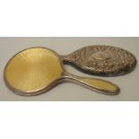 Two silver backed hand mirrors, one with embossed floral decoration, the other with inset yellow