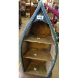 A small painted wood rowing boat shaped wall shelf with oars