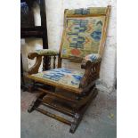 An American stained wood framed rocking chair with upholstered back, seat and armrests, set on