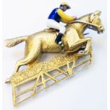 A 9ct. gold brooch in the form of a racehorse jumping a fence with coloured enamel jockey