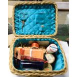 A small wicker basket containing sewing items including stork pattern scissors, etc.